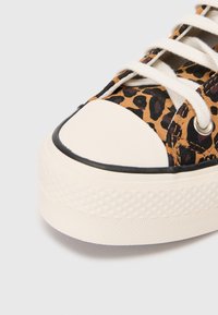 Leoparda raksta auduma tenisa kedas ar krēmkrāsas gumijas zoli un purngalu, baltām auklām un melnu apmalēm.