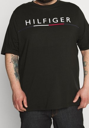 Sort t-shirt med korte ærmer og teksten "HILFIGER" i fede hvide bogstaver over brystet samt et minimalistisk design med røde og blå accenter.