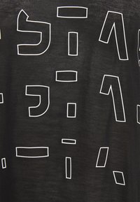 Černá tkanina s nepravidelnými bílými obrysy geometrických tvarů připomínajících stylizovaná čísla a interpunkční znaménka rozptýlená v určitém vzoru.