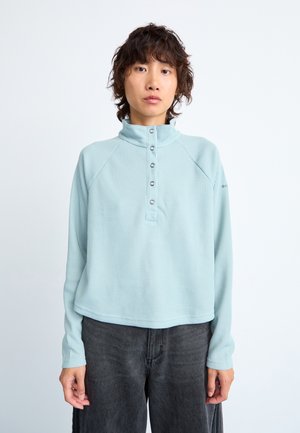 Pull léger bleu clair à côtes avec un col haut et une patte de boutonnage à cinq boutons. Présente des manches raglan et une coupe décontractée. Tissu texturé.