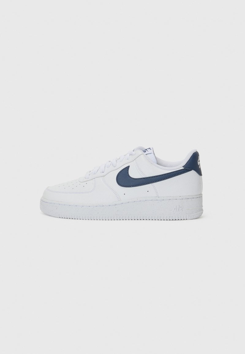 Baskets en cuir blanc avec un logo swoosh bleu marine, bout rond, lacets plats et semelle en caoutchouc texturé. Présente des perforations pour favoriser la respiration.