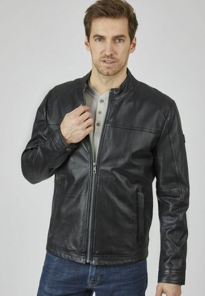 Zwarte leren jas met een hoge kraag, ritssluiting aan de voorkant, twee zijzakken en gedetailleerde stiksels op de schouders. Draag hem over een licht shirt.