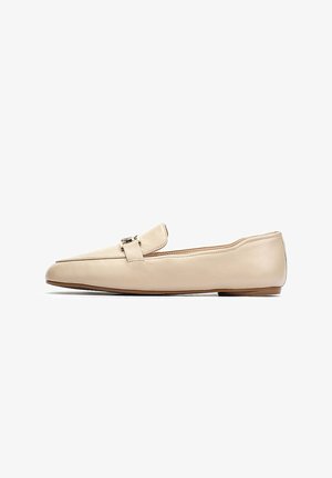 Mocasines de cuero beige con suela plana, que presentan un pequeño detalle de hebilla en la parte superior. Textura suave y diseño de punta afilada.