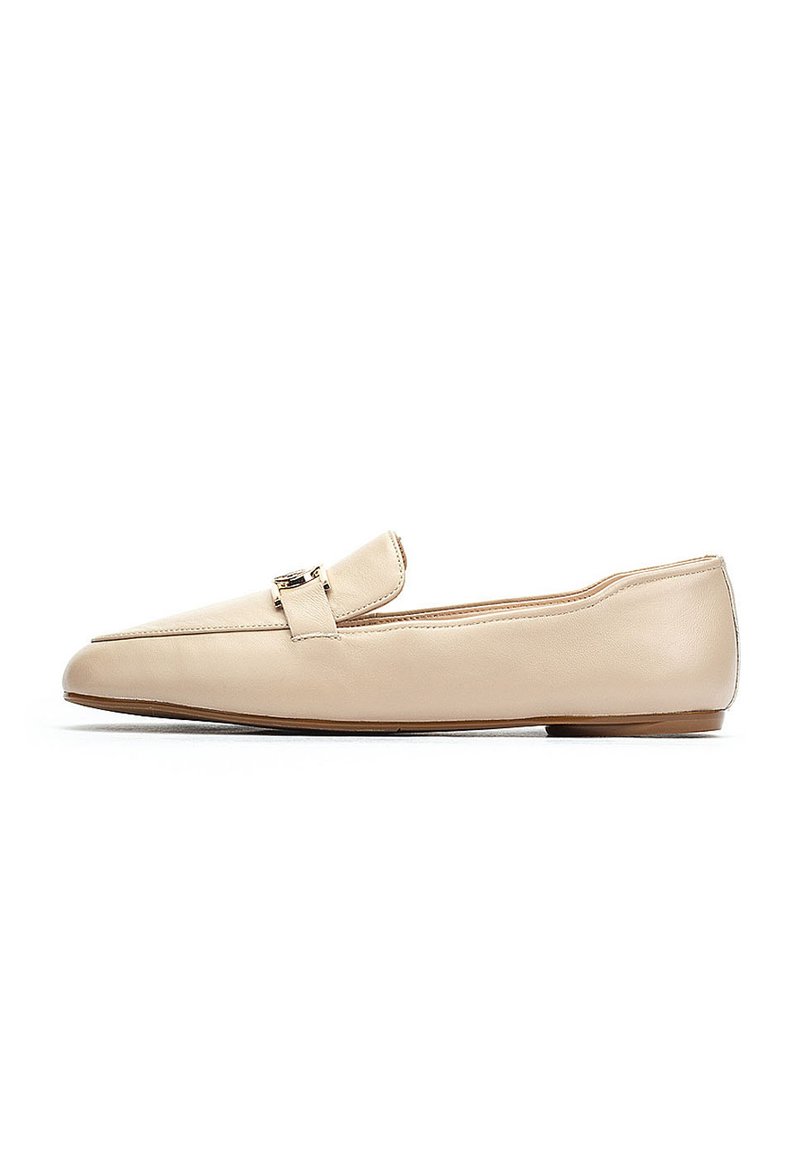Mocasines de cuero beige con suela plana, que presentan un pequeño detalle de hebilla en la parte superior. Textura suave y diseño de punta afilada.