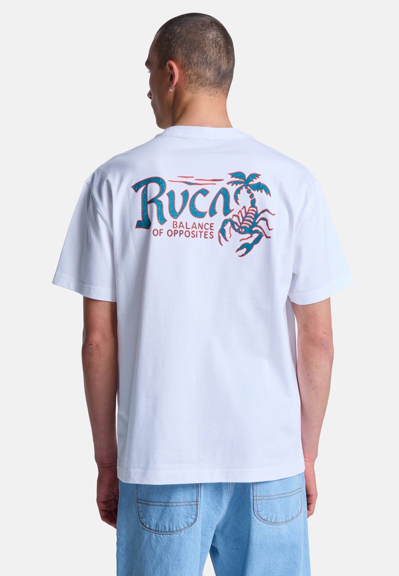 Uomo che indossa una maglietta bianca con testo blu e rosso "Rvca Balance of Opposites" e grafica di uno scorpione con palma sul retro, abbinata a jeans azzurri.