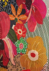 Bright floral fabric with large stylized flowers in red, orange, yellow, green, and pink on a textured, striped gray background.