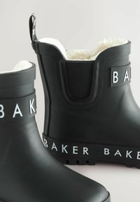 Bottes en caoutchouc noires avec un branding "BAKER" blanc, dotées d'une doublure douce et de semelles texturées, positionnées sur un fond neutre.