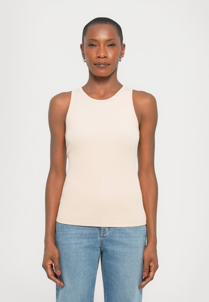 Light beige ribbed tank top with a scoop neckline and no sleeves. Paired with blue denim jeans, showcasing a snug fit and smooth texture.