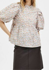 Blusa floreale con maniche corte a sbuffo, tessuto leggero, colletto rotondo e vita arricciata. Presenta una stampa floreale multicolore su uno sfondo chiaro.