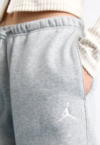 Graue Jogginghose aus einem weichen, strukturierten Stoff. Verfügt über einen elastischen Bund und Seitentaschen. Zeigt ein weißes Jumpman-Logo.