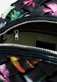 Bolso de mano negro con estampado floral y cierre con cremallera. Presenta un material texturizado y herrajes de cremallera en plata. Interior forrado en verde oliva.
