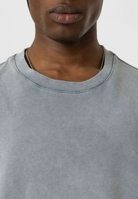 Grijze katoenen sweatshirt met een ronde hals en zichtbare stiksels. De stof heeft een gladde textuur met een licht vervaagde uitstraling.