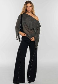 Jeans negros de pierna ancha con detalles de tachuelas plateadas, combinados con un top brillante con escote off-shoulder en gris oscuro. Ambos estilos presentan diseños sueltos y fluidos.