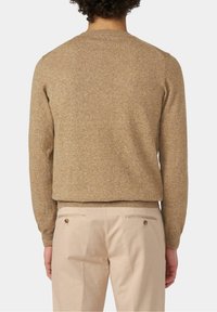 Brun, texturerad tröja med rund halsringning och långa ärmar, bärs över ljusbeiga byxor med bakfickor och knappdetalj.