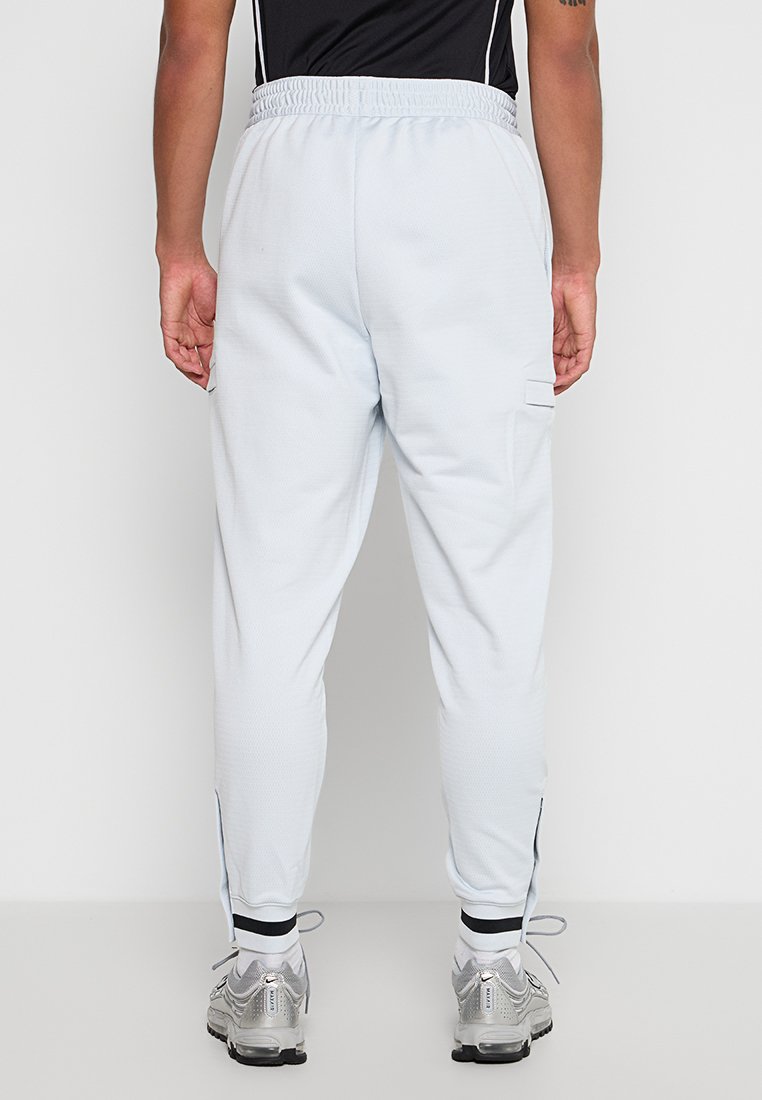 Lichtblauwe joggers met een textuurafwerking, elastische tailleband, zijzakken en zwarte accenten langs de naden. Gecombineerd met zilveren sneakers.