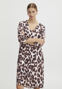 Robe en imprimé léopard avec un décolleté en V et des manches trois-quarts. Fabriquée en tissu léger, présentant des motifs marron foncé et beige clair.