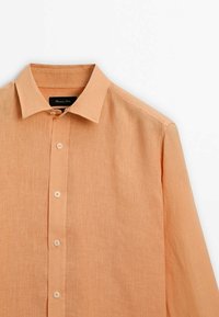 Chemise orange clair à manches longues avec boutons et col pointu, réalisée en tissu texturé, présentée sur fond blanc.