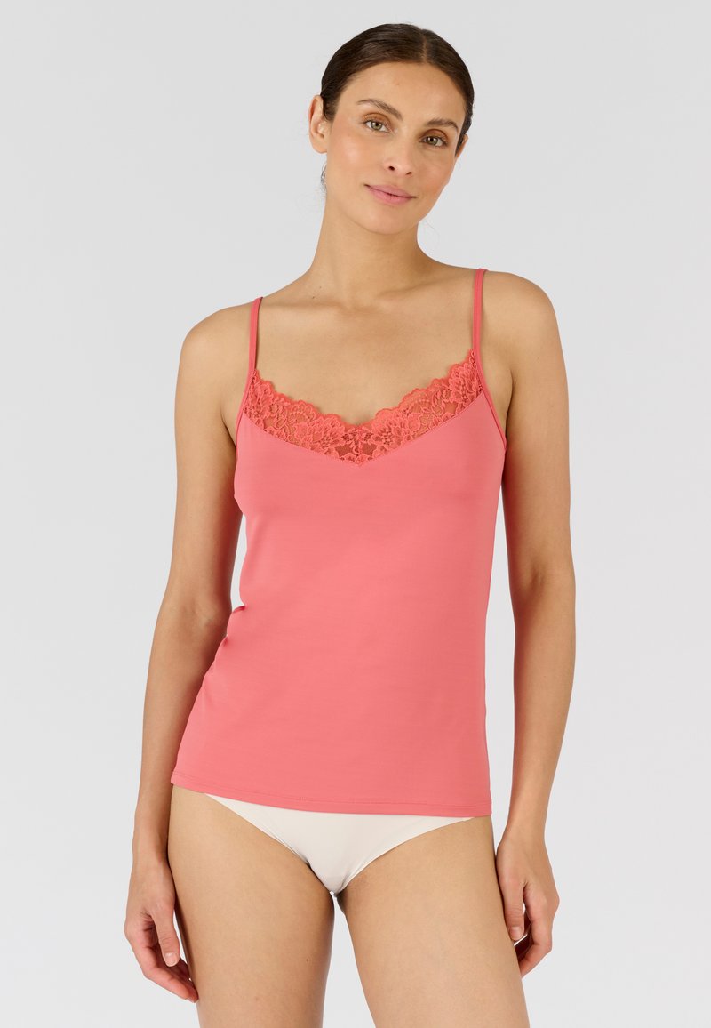 Top in corallo con pizzo lungo il collo. Presenta spalline sottili e un design aderente. Tessuto morbido con una consistenza liscia.