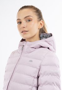 Giacca imbottita rosa chiaro con cappuccio, caratterizzata da un logo argento, chiusura con zip e texture trapuntata per l'isolamento. Design slim fit.