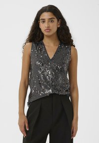 Ujjatlan sötétszürke felső V-nyakkivágással, ezüst flitterekkel díszítve, melyek függőleges csíkokban helyezkednek el, puha tapintású, laza fazonú.