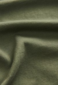 Olivgrüner Baumwollstoff mit einer glatten, feinen Textur, die leicht zerknittert und gefaltet ist. Keine Muster oder zusätzlichen Details sichtbar.