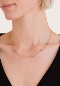 Zlatý náhrdelník s více malými, průhlednými drahokamy. Jemný design s rovnoměrně rozmístěnými akcenty, ideální na vrstvení.