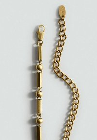 Goldene Kettenarmband mit abwechselnd zylindrischen und sphärischen Perlen, ausgestattet mit einem sicheren Karabinerverschluss. Strukturierte Glieder und Markendetails sind vorhanden.