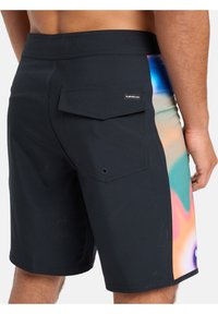 Pantaloni scurți negri cu un design abstract multicolor pe lateral. Au o buzunar pe spate și accente cusute. Textură netedă, lungime până la genunchi.