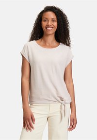 Chemise courte à manches courtes beige clair avec un motif texturé et un nœud noué à la taille, fabriquée dans un tissu doux et respirant.