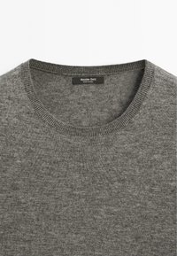 Maglione grigio in maglia con scollatura rotonda, realizzato in tessuto morbido, con colletto a costine e etichetta con la scritta "Massimo Dutti."