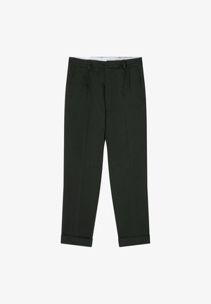 Witte t-shirt met korte mouwen, gecombineerd met donkergroene, op maat gemaakte broek met een relaxte pasvorm en opgerolde mouwen, aangevuld met witte sneakers.