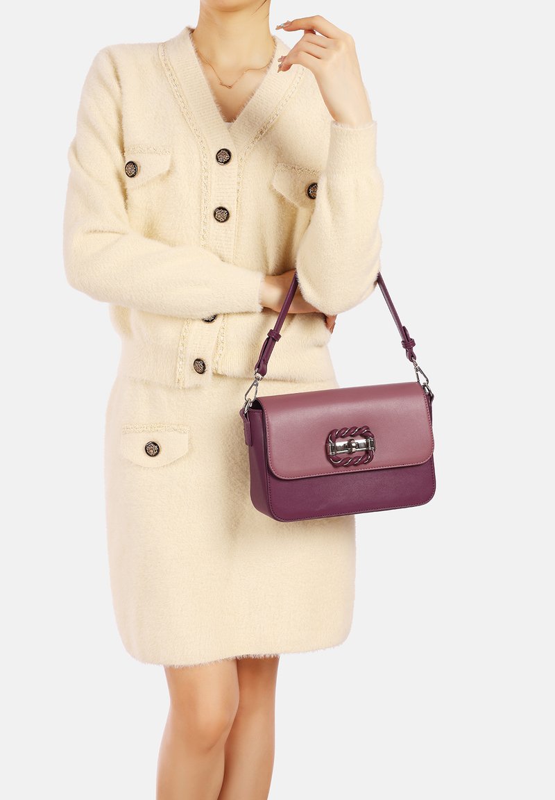 Vestito cardigan in pelliccia color crema con bottoni e tasche, abbinato a una borsa a due tonalità di viola con dettagli in catena e tracolla regolabile.