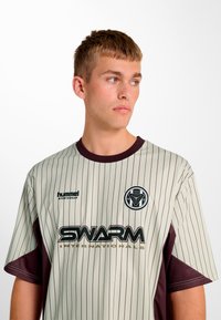 Gestreiftes Kurzarmtrikot in Hellgrün und Dunkelrot mit rundem Ausschnitt, SWARM-Logo und feiner Struktur im Stoff.