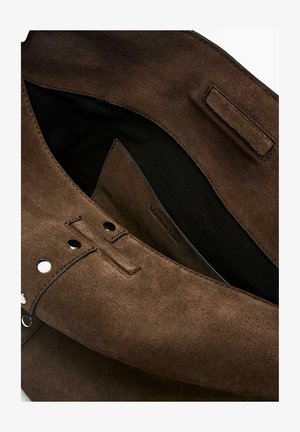 Tmavě hnědá kabelka z semiše s černým látkovým vnitřkem, magnetickými zapínáními a viditelným prošíváním na čistě bílém pozadí.