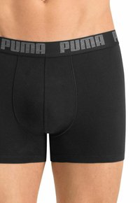 Black boxer briefs made of smooth fabric, featuring a gray elastic waistband with "PUMA" logo. Fitted shape with a contoured pouch.