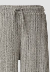 Graue, strukturierte Jogginghosen mit einer Kordelzug-Taille, die ein einzigartiges Muster aufweisen und aus weichem Material bestehen. Sie sind ideal für Freizeitaktivitäten oder zum Entspannen.
