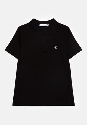 Polo noir à manches courtes avec col, petit patch logo Calvin Klein Jeans sur le côté gauche de la poitrine, et patte de boutonnage.