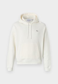 Sudadera blanca hecha de una tela suave, con un bolsillo frontal, capucha ajustable con cordón y un pequeño logo verde de Lacoste en el pecho.