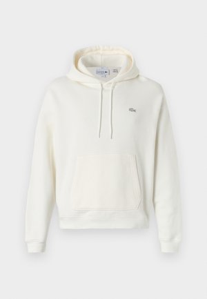 Hvit hettegenser laget av mykt stoff, med frontlomme, justerbar snøring i hetta og en liten grønn Lacoste-logo på brystet.
