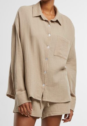 Beige, teksturoitu puuvillapaita, jossa on kaulus, etunapit ja rintatasku, yhdistetty rentoihin, samanvärisiin shortseihin.