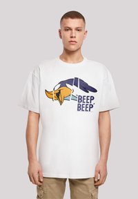 Hvit bomull t-skjorte med et stort grafisk motiv av hodet til en tegneseriefigur med teksten "BEEP BEEP" i blått. Løs passform og korte ermer.