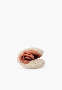 Baskets souples beige et rose pliées en deux, mettant en valeur la semelle douce et flexible ainsi que la tige en tissu de la chaussure.