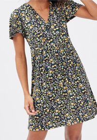 Robe fleurie avec un décolleté en V, des petites manches et une taille cintrée. Présente un fond marine avec des motifs floraux jaunes, bleus et verts.