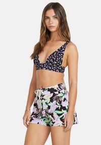 Marineblå, blomstret bikinitopp med dyp V-hals og brede bånd, paret med høy midje badedraktshorts med tropisk mønster i pastellfarger.