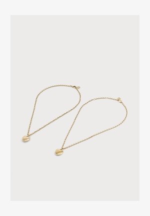 Zwei goldene Halsketten, jede mit einem kleinen herzförmigen Anhänger auf einem schlichten hellen Hintergrund.