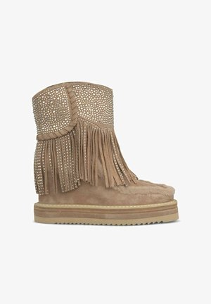 Bottines en suède beige avec des détails en franges, des accents cloutés et une doublure en fausse fourrure, dotées d'une semelle en caoutchouc plate et d'un bout arrondi.