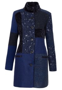 Blå lapptäckesjacka med krage, blandade texturer och fem svarta knappar. Olika nyanser och mönster skapar en visuellt slående design.