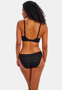Set di lingerie nero con motivo in pizzo geometrico, bretelle regolabili e chiusura a gancio sul reggiseno. Le mutandine hanno una vestibilità a vita bassa.