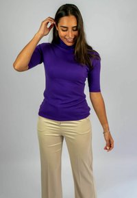 Paars turtleneck trui met korte mouwen, gecombineerd met beige wijde broek. De gladde textuur, de aansluitende pasvorm en de zachte stof zorgen voor een verzorgde uitstraling.