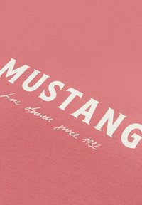 Roze sweatshirt met "MUSTANG" in dikke witte letters, en kleinere tekst "true denim since 1932", met een soepele, textuurachtige stof.